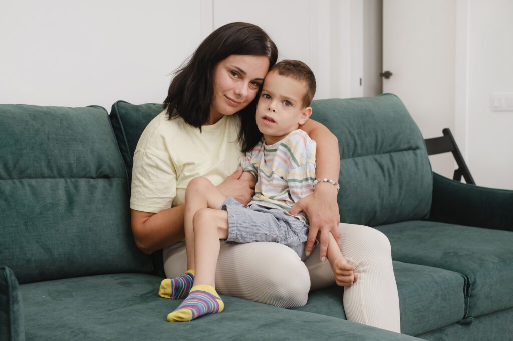 .Mother with disabled child with cerebral palsy on sofa having fun